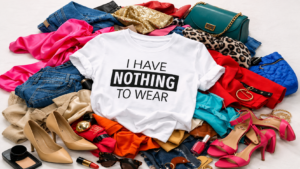White T‑shirt reading ‘I Have Nothing To Wear’ placed on a pile of colourful clothes and accessories, representing a fashion makeover